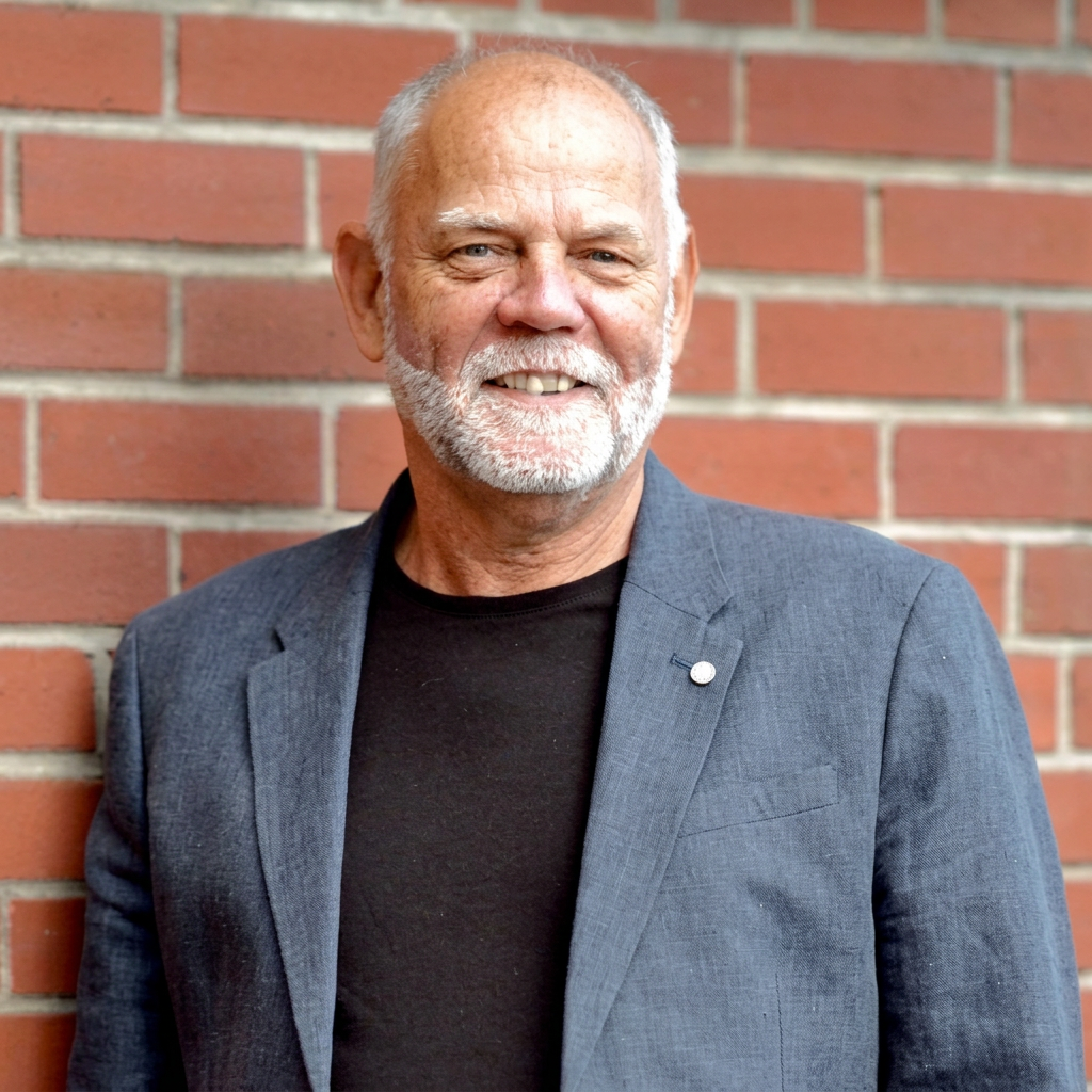 Earl Storey in a jacket standing in front of a brick wall